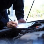 A person writing vehicle details about MOT Test